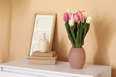 Kadınlar Günü için laleli vazo, oturma odasında klozette kitaplar ve çerçeveler.