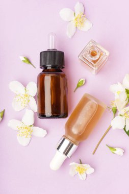 Esaslı yağ şişeleri ve leylak arkaplanda güzel yasemin çiçekleri olan kompozisyon