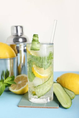 Barmen aletleriyle beyaz duvarın yanındaki mavi masada bir bardak mojito.