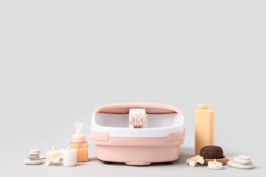 Ayak banyosu, kozmetik ürünleri, sünger taşları ve gri arka planda kaplıca taşları