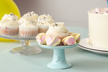 Turkuaz masada doğum günü partisi için lezzetli beyaz kek ve şekerlemelerle tatlı standı.