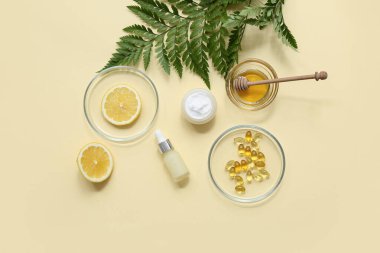 Sarı arka planda doğal kozmetik ürünleri hazırlamak için gerekli malzemelerle dolu şişeler ve Petri kapları.