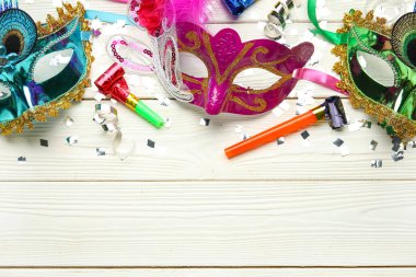 Parti boynuzları ve beyaz ahşap arka planda konfeti olan güzel karnaval maskeleri. Üst görünüm