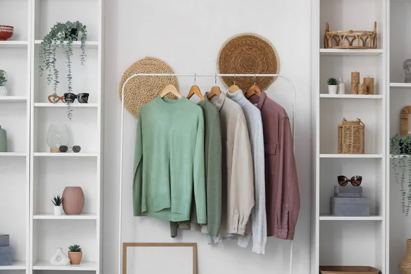 Giysi askılığı ve rafları beyaz duvarın yanında olan modern soyunma odasının içinde.