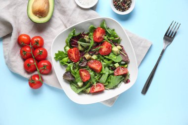 Çeri domatesli avokado salatası ve mavi arka planda baharatlar.