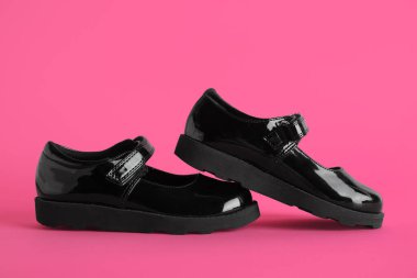 Pembe arka planda siyah bir kızın ayakkabıları.