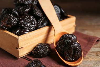 Tahta arka planda kurutulmuş kuru erikli kutu ve kaşık.