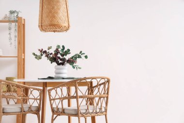 Yemek masasında okaliptüs dalları ve peçeteli vazo.