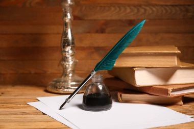 Ahşap arka planda kalem, mürekkep hokkası ve kağıt çarşaflı kitaplar