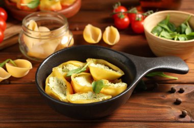 Peynirli, domatesli ve ahşap zemin üzerinde ıspanaklı koni dolması.