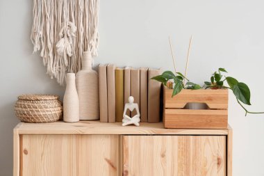 Kutulu çekmeceler, dekoratif şişeler ve beyaz duvarın yanındaki kitaplar, yakın plan.