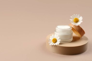 Dekoratif podyum, kahverengi arka planda papatya çayı ve çiçek kavanozu.