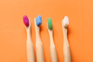Turuncu arka planda farklı bambu diş fırçaları.