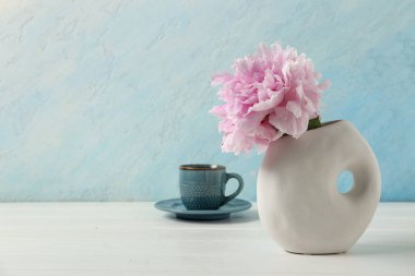 Güzel şakayık çiçekli vazo ve mavi duvarın yanındaki masada bir fincan çay.