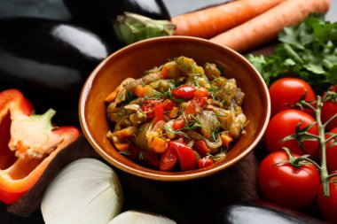 Bir kase sebze yahnisi domatesli, patlıcanlı, havuçlu ve kahverengi peçeteli.