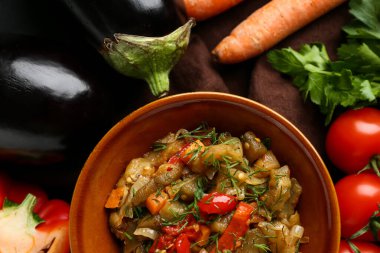 Bir kase sebze yahnisi domatesli, patlıcanlı, havuçlu ve kahverengi peçeteli.