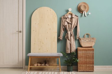 Raflar, ahşap tezgah, ev bitkileri, bankta ayakkabılar ve mavi duvarda asılı sonbahar ceketi olan modern koridorun içi.