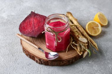 Gri grunge arka planda pancar, limon ve kaşıkla turp sosu kavanozu yakın plan.