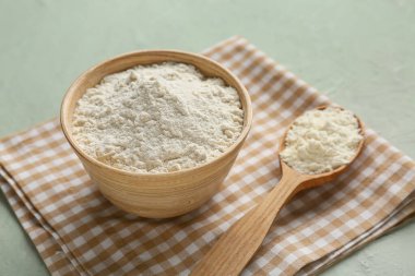 Gri arkaplanda tahta kaşıkla bir kase süt tozu.