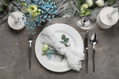 Güzel çiçekler ve gri arka planda okaliptüs dallarıyla düğün için şık bir masa.