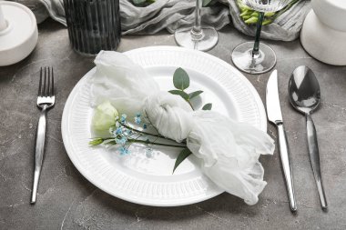 Gri arka planda güzel çiçekler ve okaliptüs dallarıyla düğün için şık bir masa. Yakın plan.