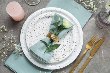 Gri arka planda güzel çiçekler, mum ve okaliptüs dallarıyla düğün için şık bir masa.