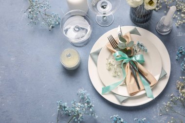 Düğünümüz için güzel bir masa, çingene çiçekleri ve mavi arka planda mumlar.