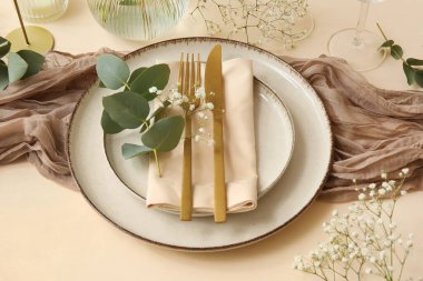 Altın çatal bıçak takımı ve renk arkaplanlı çigila çiçekleriyle düğün için şık bir masa.