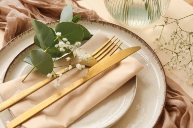 Altın çatal bıçak takımı ve renk arkaplanlı çigila çiçekleriyle düğün için şık bir masa.