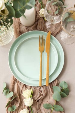 Altın çatal bıçak ve güzel çiçeklerle düğün için şık bir masa.