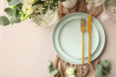 Altın çatal bıçak ve güzel çiçeklerle düğün için şık bir masa.