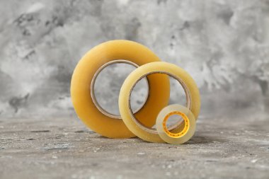 Gri arkaplanda farklı yapışkan bant ruloları