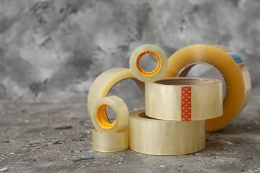 Gri arkaplanda farklı yapışkan bant ruloları