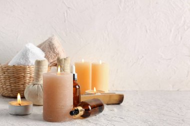 Havlular, yanan mumlar ve beyaz arka planda kaplıca malzemeleri olan bir sepet.