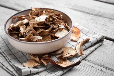 Bej ahşap arka planda kurutulmuş mantarlı kase.