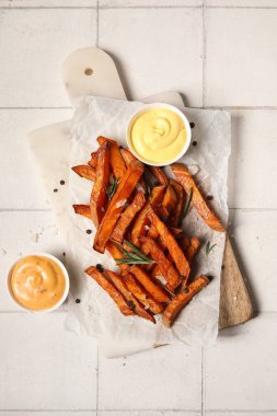 Lezzetli pişmiş patates, bir kase sos ve beyaz fayanslı biberiye.