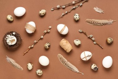 Easter eggs with feathers, gypsophila flowers and pussy willow branches on brown background