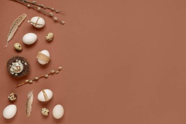 Easter eggs with feathers, gypsophila flowers and pussy willow branches on brown background