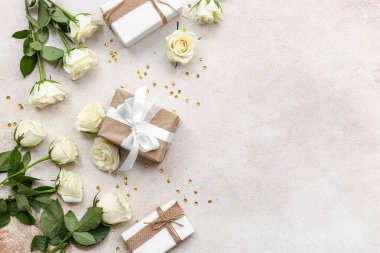 Gri arkaplanda hediye kutuları olan güzel beyaz güller.