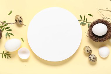 Paskalya yumurtaları, yapraklar ve bej arka planda ağaç dalları olan boş kart