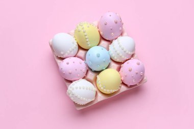Paskalya yumurtaları pembe arka planda incilerle süslenmiş.