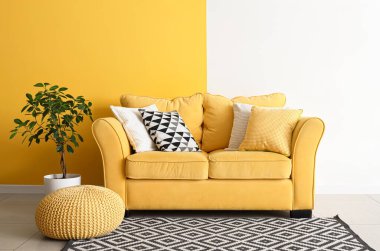 Sarı kanepesi, puf ve bitkisi olan şık bir oturma odası.