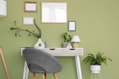 Okaliptüs dallı vazo ve lamba yeşil duvarın yanındaki odada.