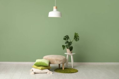 Rahat pouf, sehpa, çiçek ve beyaz lambayla şık bir oturma odası.