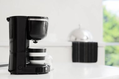 Mutfakta fincanı olan, modern siyah kahve makinesi.