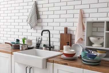 Mutfak tezgahında lavabo, temiz tabaklar ve havlular asılı.