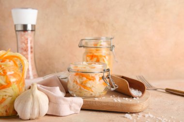 Lezzetli lahana turşulu cam kavanozlar ve bej arka planda bir şişe tuz. Yakın çekim.