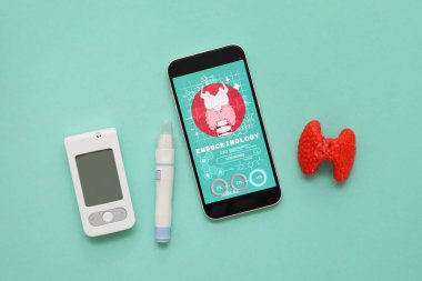 Glukometresi olan cep telefonu, tükenmez kalem ve yeşil arka planda tiroit bezi modeli. Endokrinoloji kavramı