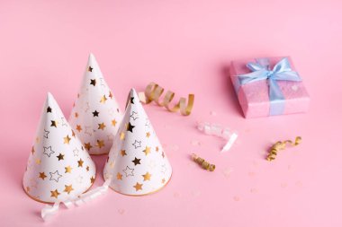 Hediye kutulu parti şapkaları ve pembe arka planda yılan balığı.