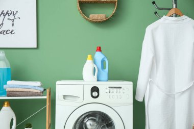 Modern çamaşır makinesi, bornoz ve deterjan şişeleriyle şık bir çamaşır odası.